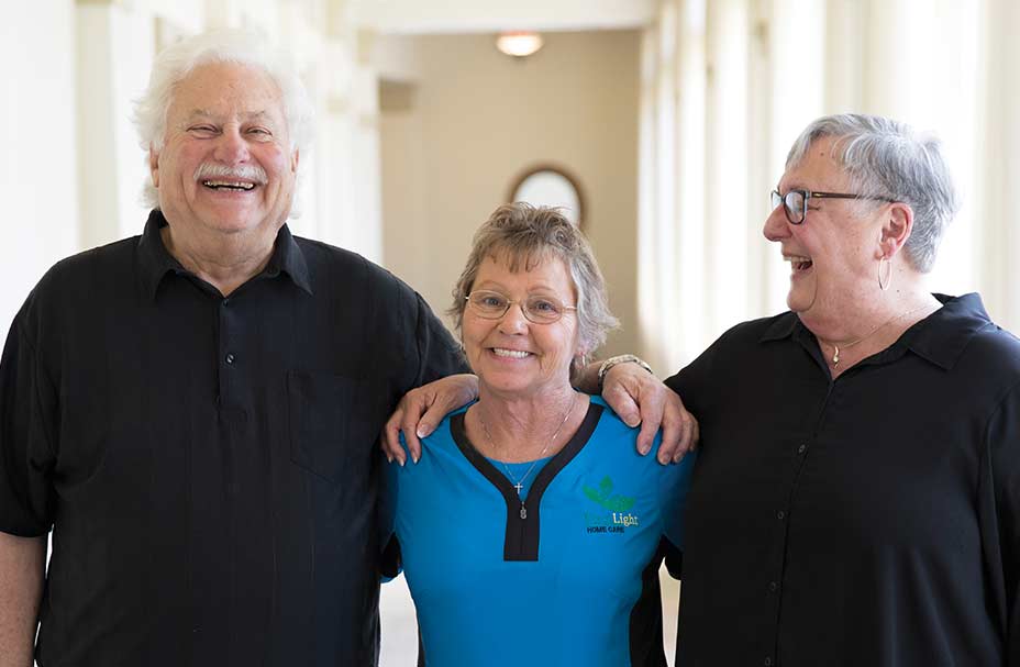 A caregiver stands between the franchise owners at her local office