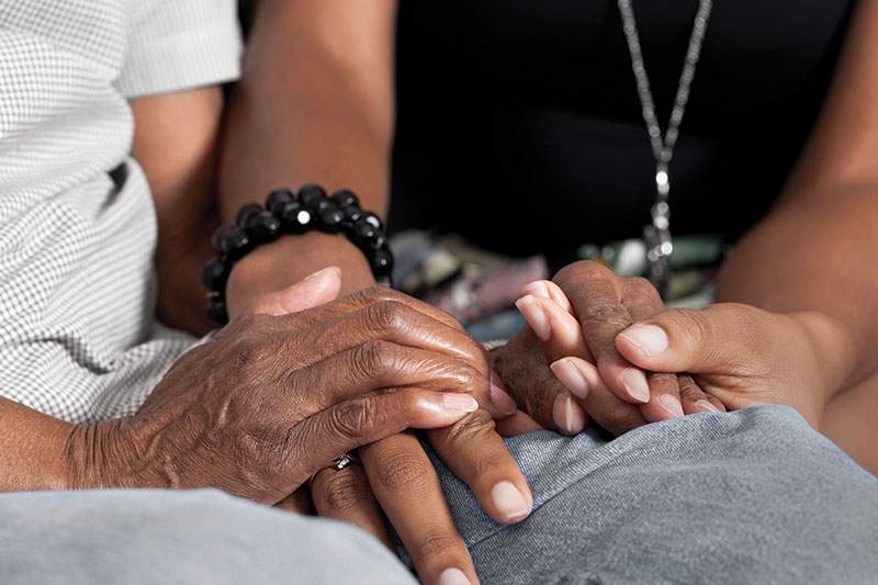 two people holding hands sitting side by side